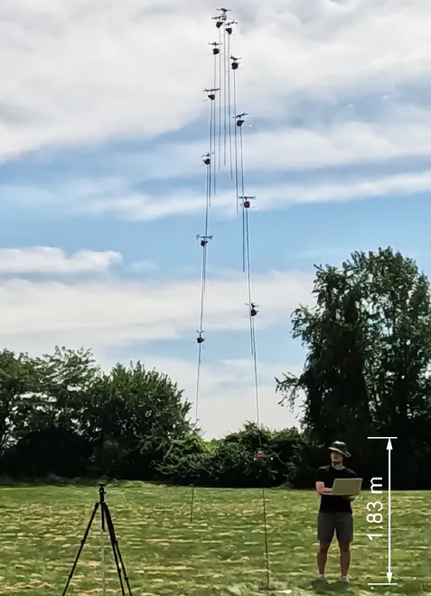 A robot shown at many positions during one jump, rising high above a person standing on a grassy field.