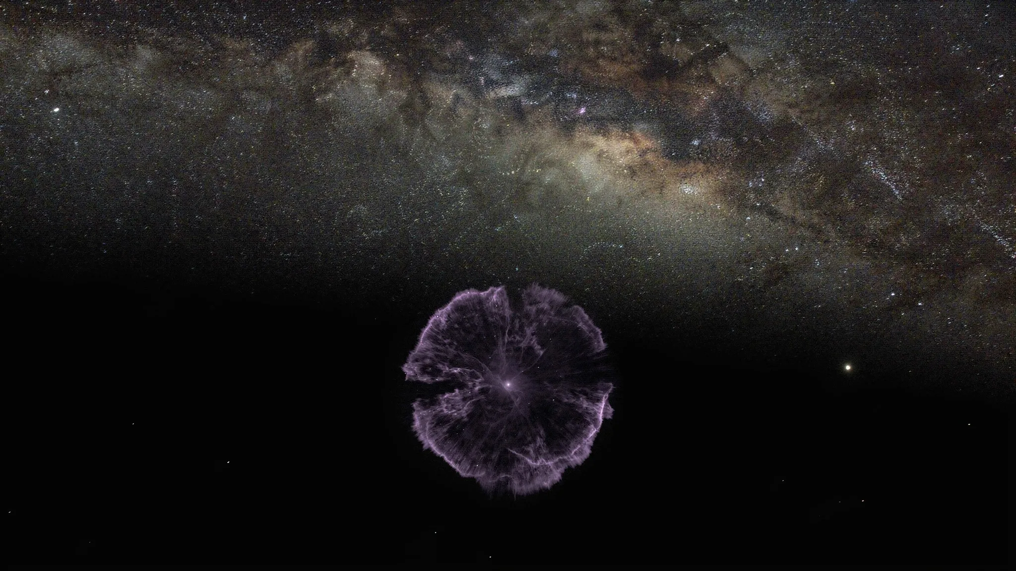 A faint, roughly round cloud of glowing debris against a dense star field, lit in violet.