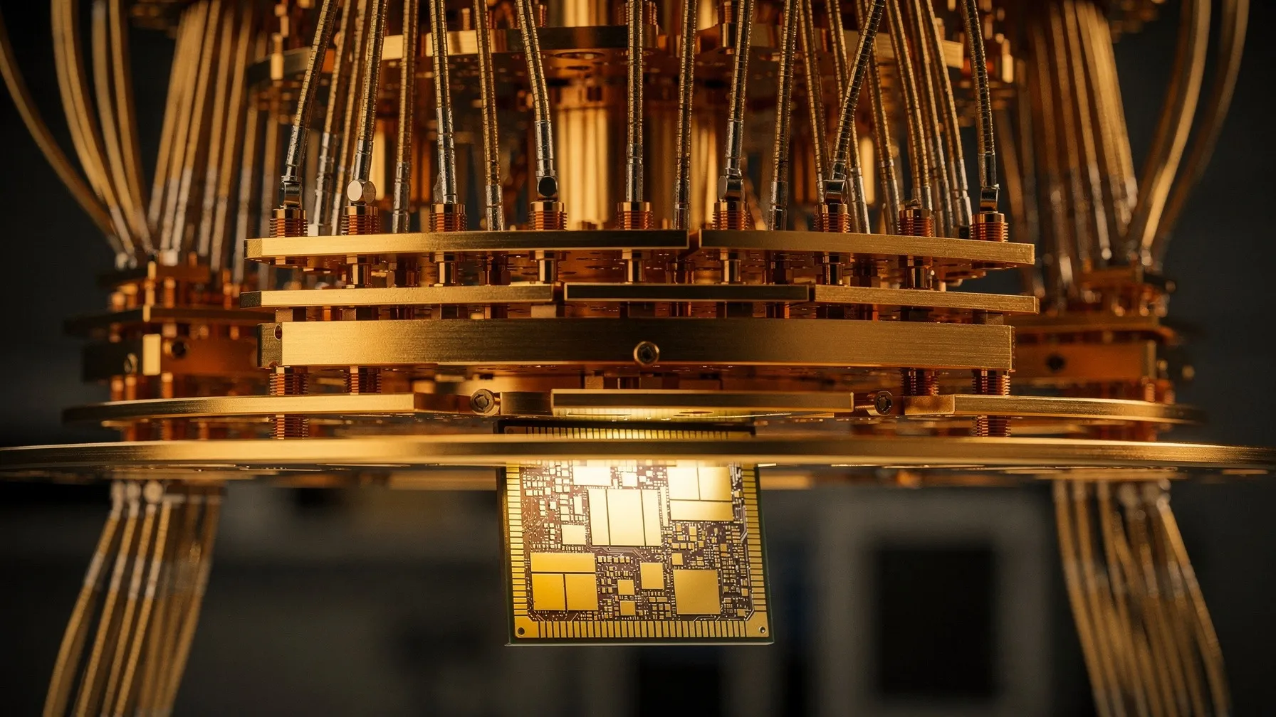 Close-up of a square quantum processor chip at the bottom of a gold-plated cryogenic chandelier with cables and copper plates.